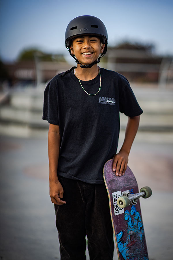 Kage smiling at the camera with his skateboard in hand.