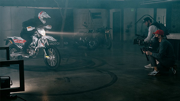 Behind the scenes image of videographer filming a motorcycle rider doing donuts