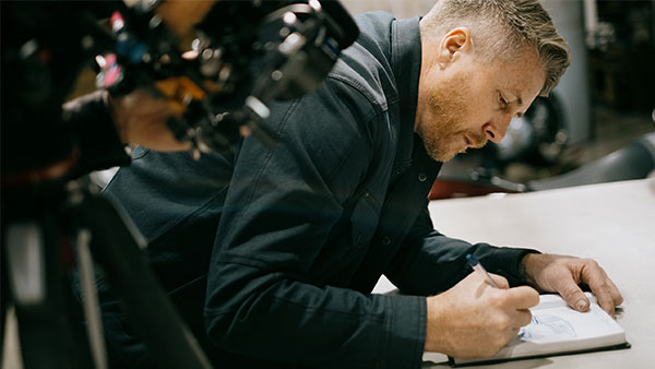 Behind the scenes image of Roland Sands drawing in a notebook