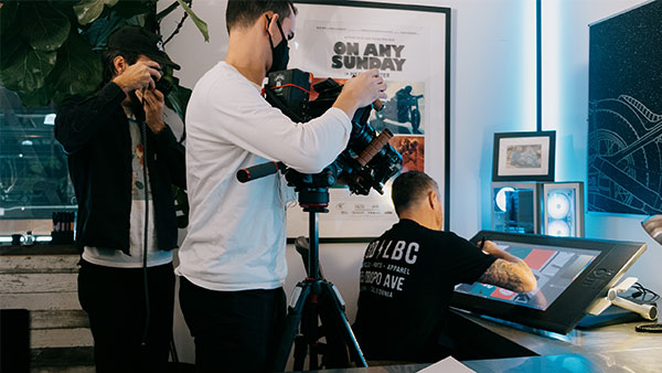 Behind the scenes image of videographer and photographer capturing Roland Sands drawing on a computer screen